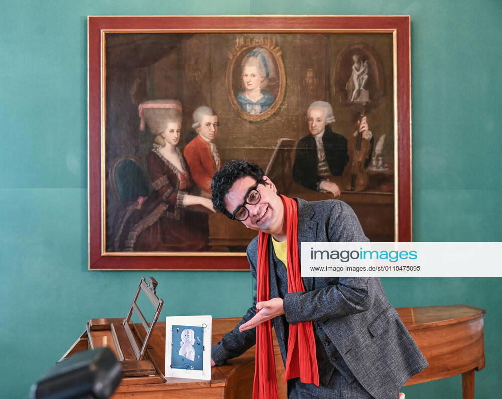 Pressekonferenz zur Programmpräsentation der Mozartwooche 2022 in Salzburg, am 19.05.21. Das Bild zeigt den Intendaten der Mozartwochen, Rolando Villazon während seines Vortrags zur Programmpräsentation. Im Hintergrund ist ein Bild der Familie Mozart zu sehen. Herr Villazon steht vor einem Tasteninstrument und deutet auf einen Programmkatalog. 2021 - Pressekonferenz zur Programmpräsentation der Mozartwooche 2022 in Salzburg, am 19.05.21