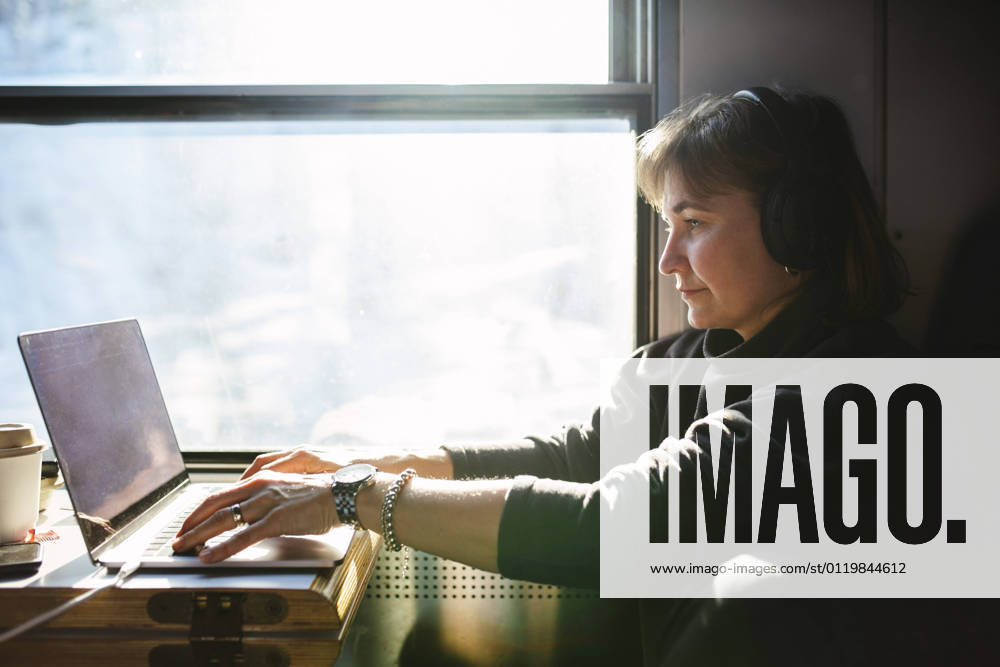 Businesswoman using laptop while sitting by window in train Sweden, Kiruna, model released
