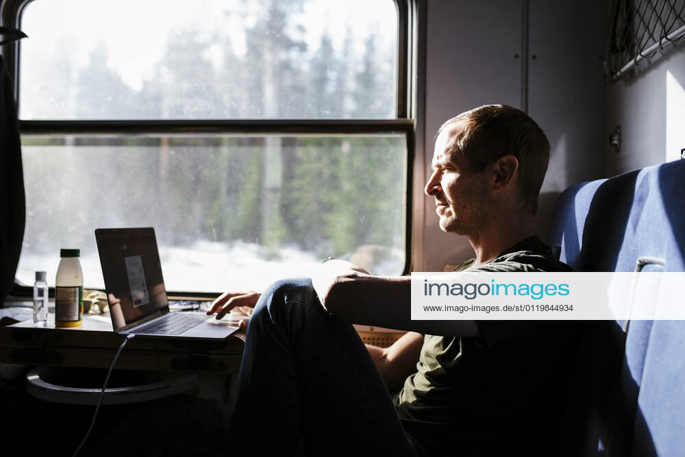 Businessman using laptop while sitting by window in train Sweden, Kiruna, model released