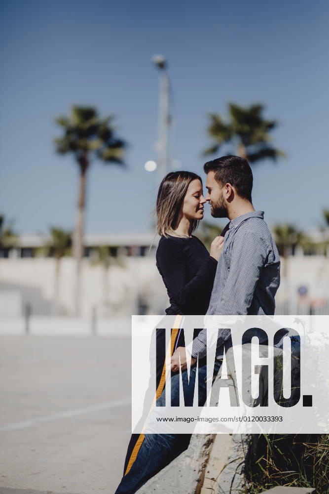 Bearded man hugging laughing woman while spending time on green lawn on street together, Model released