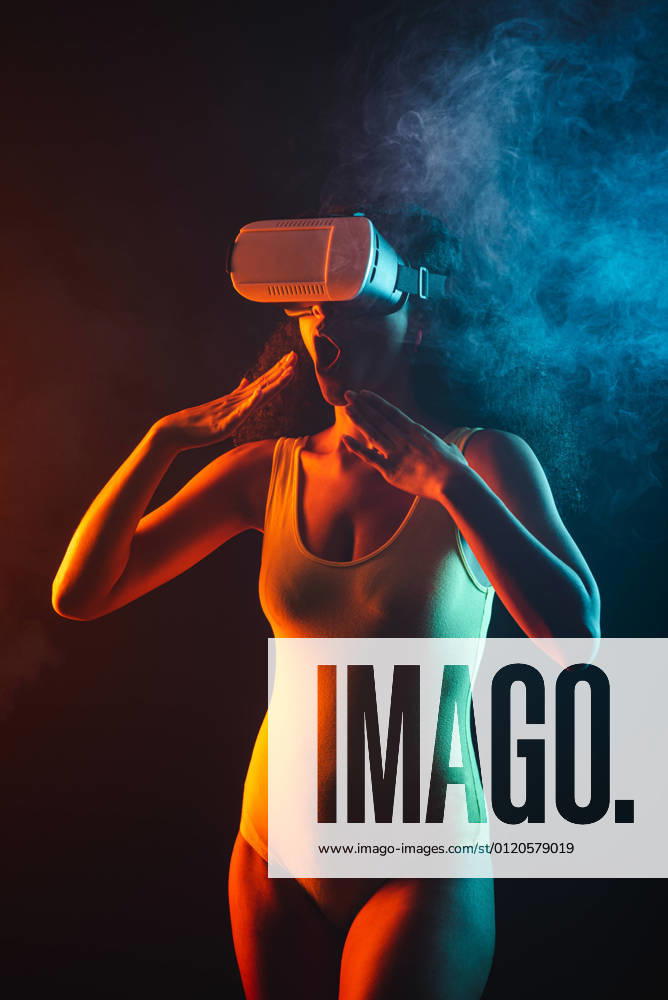 Anonymous astonished ethnic female with open mouth exploring virtual reality in headset on black background, Model released