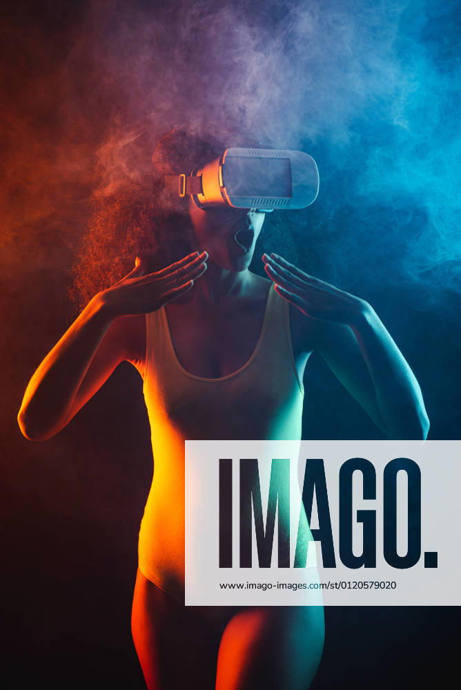 Anonymous astonished ethnic female with open mouth exploring virtual reality in headset on black background, Model released