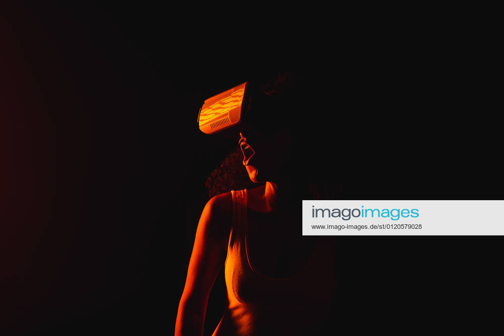 Anonymous astonished ethnic female with open mouth exploring virtual reality in headset on black background, Model released
