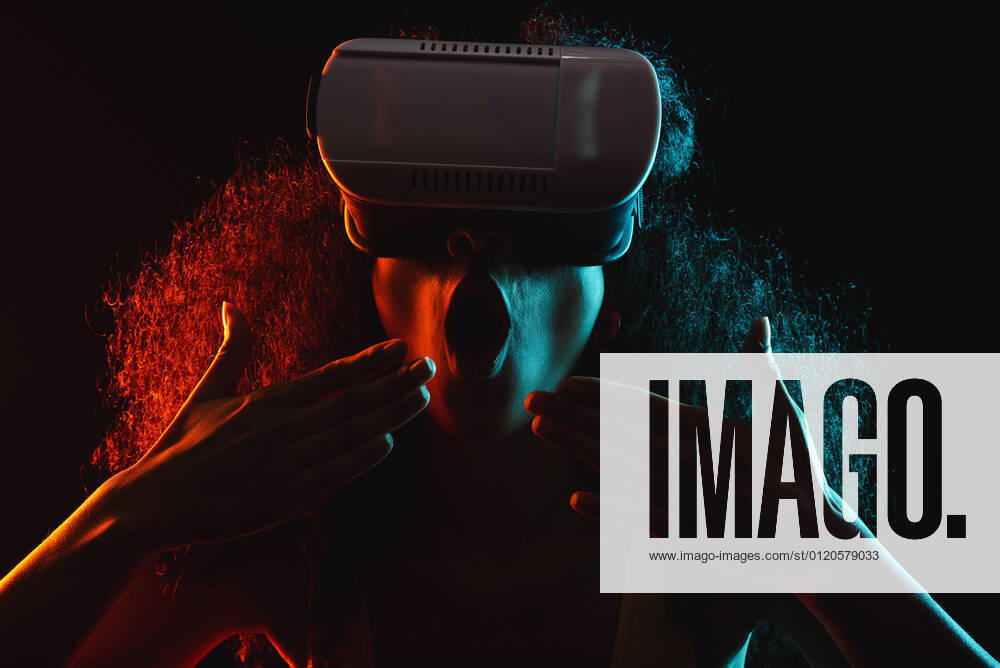 Anonymous astonished ethnic female with open mouth exploring virtual reality in headset on black background, Model released