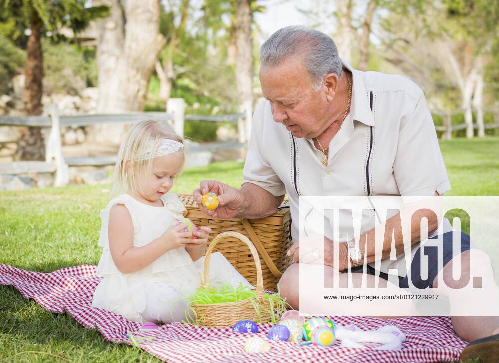 Liebevolle Großvater und Enkelin genießen Ostereier auf einer Picknickdecke im Park