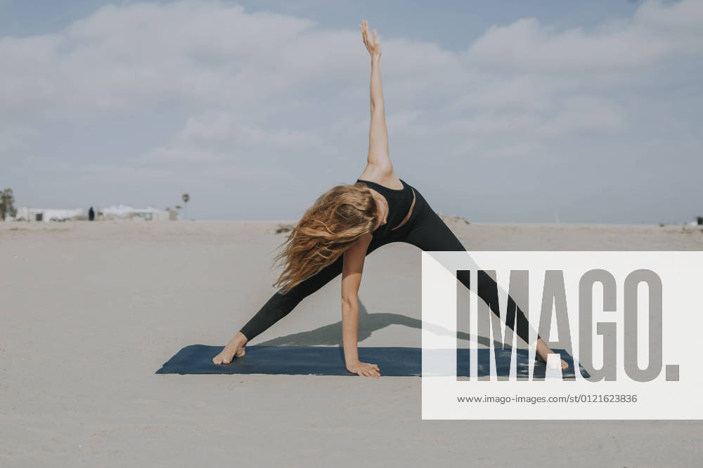 IMAGO Creative: Clickbait, Sport und Fitness Female athlete practicing yoga on exercise mat at beach model released Symbolfoto OIPF00650