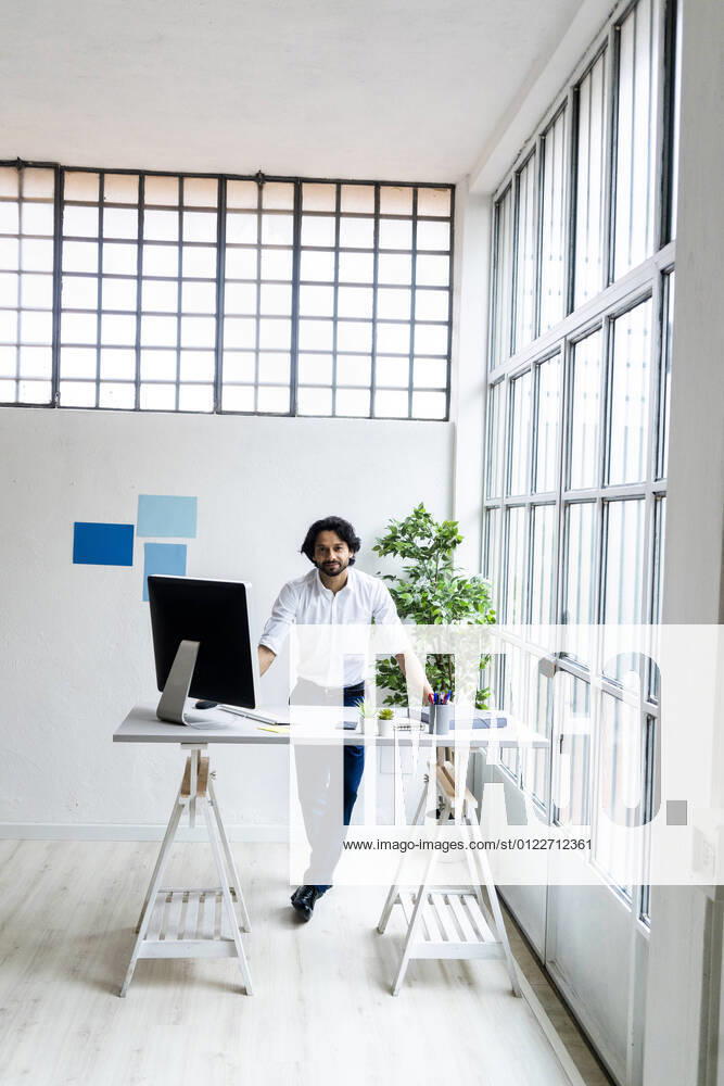 Young businessman standing by desk in office model released Symbolfoto property released GIOF12869