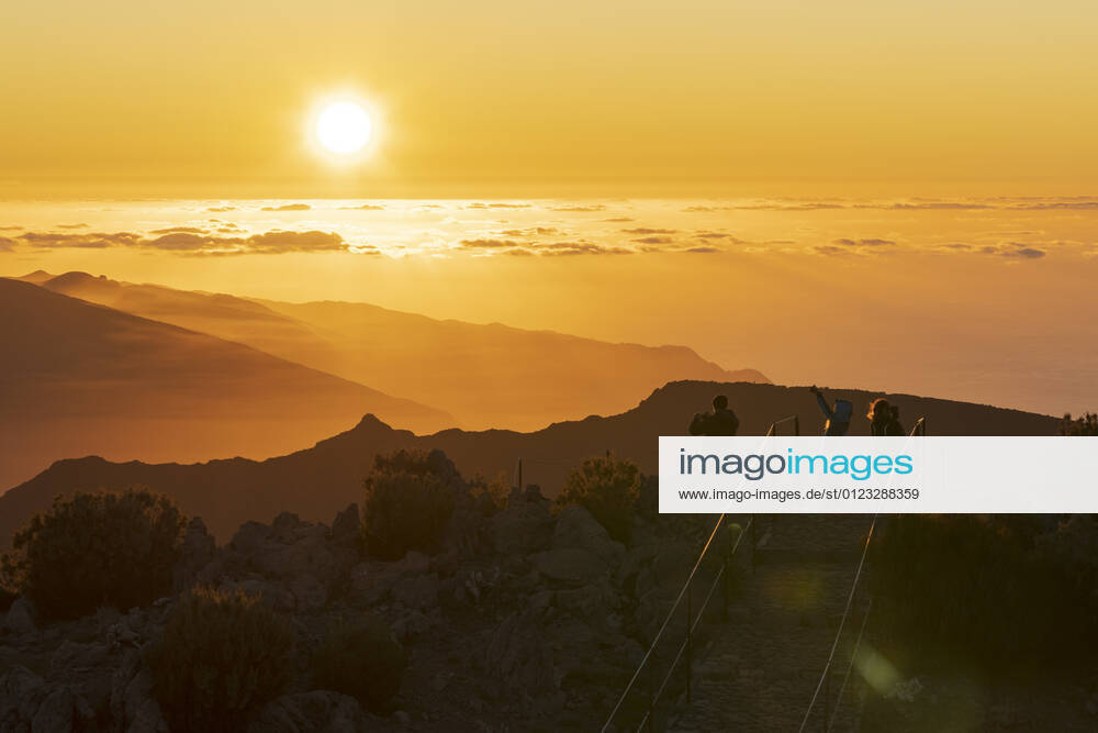 Tourists photographing sunset with smartphone from Pico Ruivo mountain peak, Madeira, Portugal, Atlantic, Europe