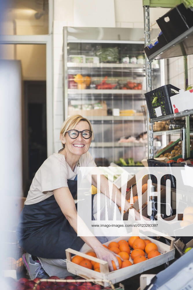IMAGO Creative: Kreative Renaissance -- der junge Entrepreneur Portrait of smiling female owner arranging fruits in rack at store Sweden, Stockholm, model released, property released