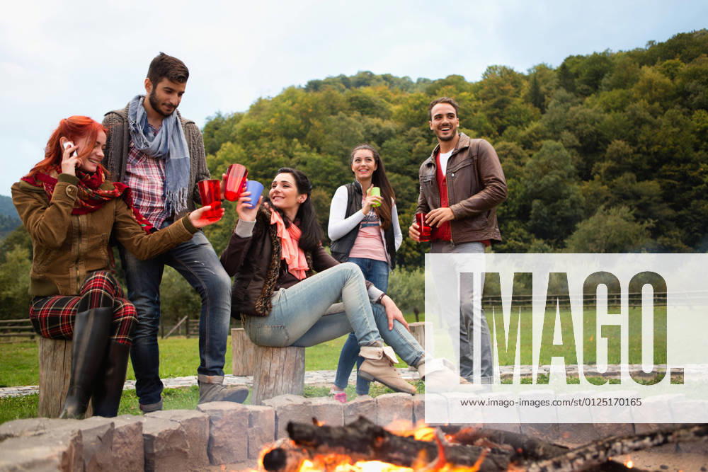 Group of people standing around campfire.