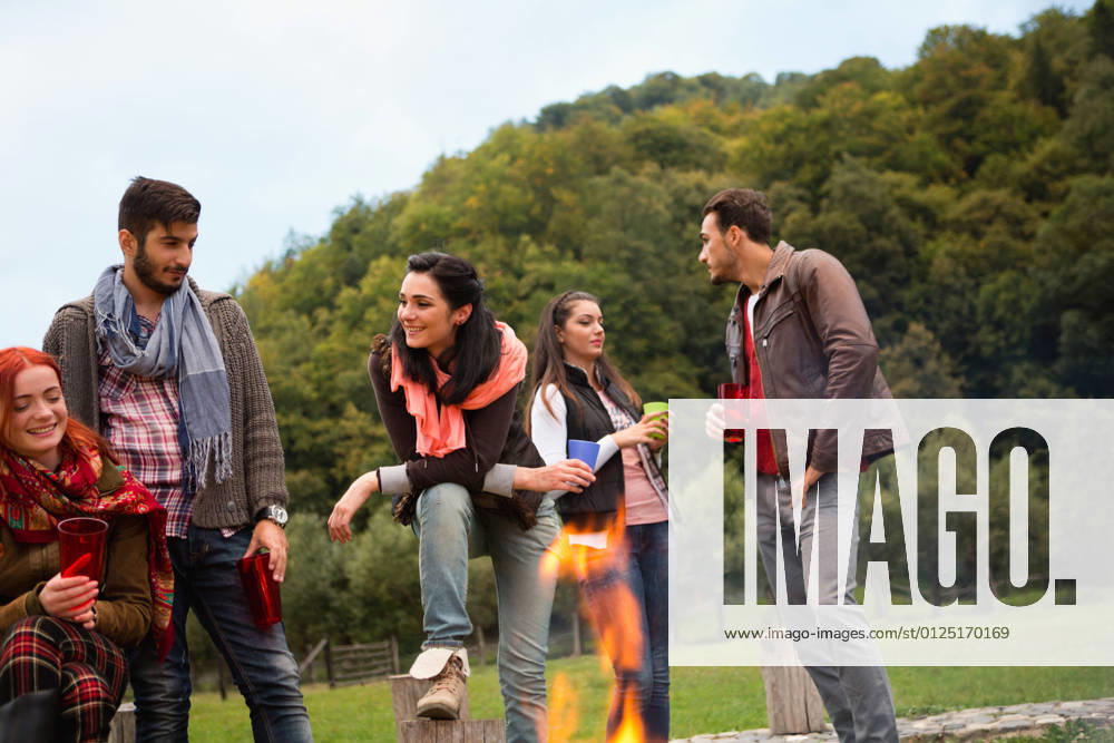 Group of people standing around campfire.