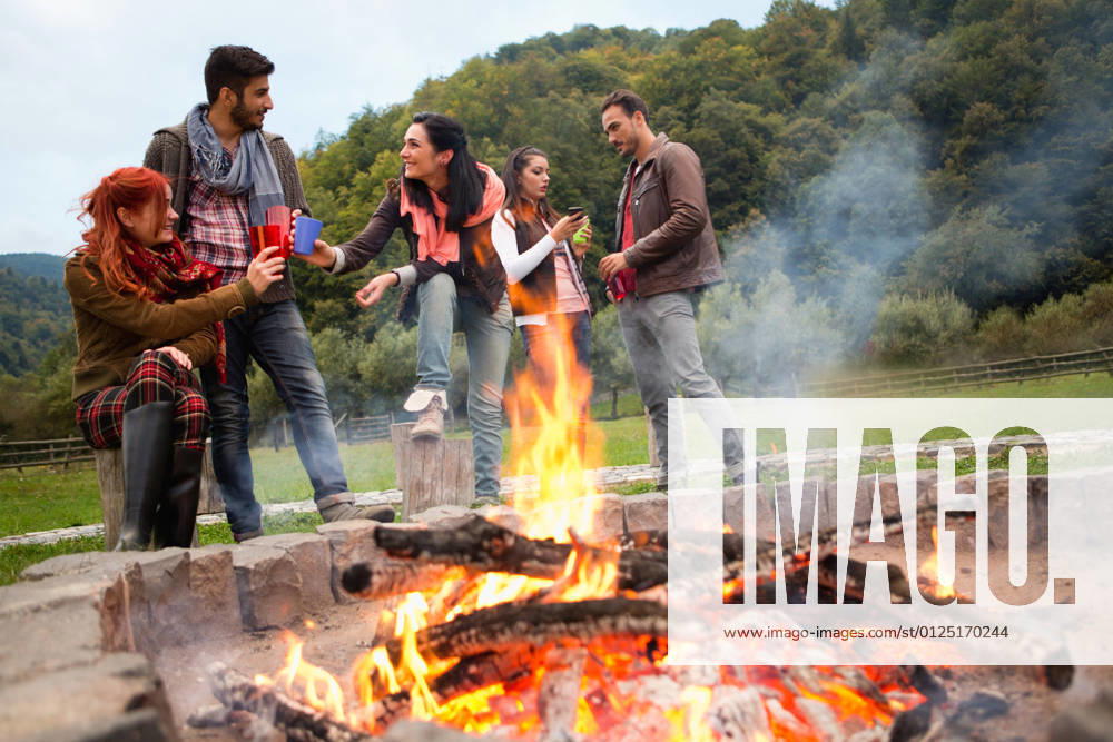 Group of people standing around campfire.