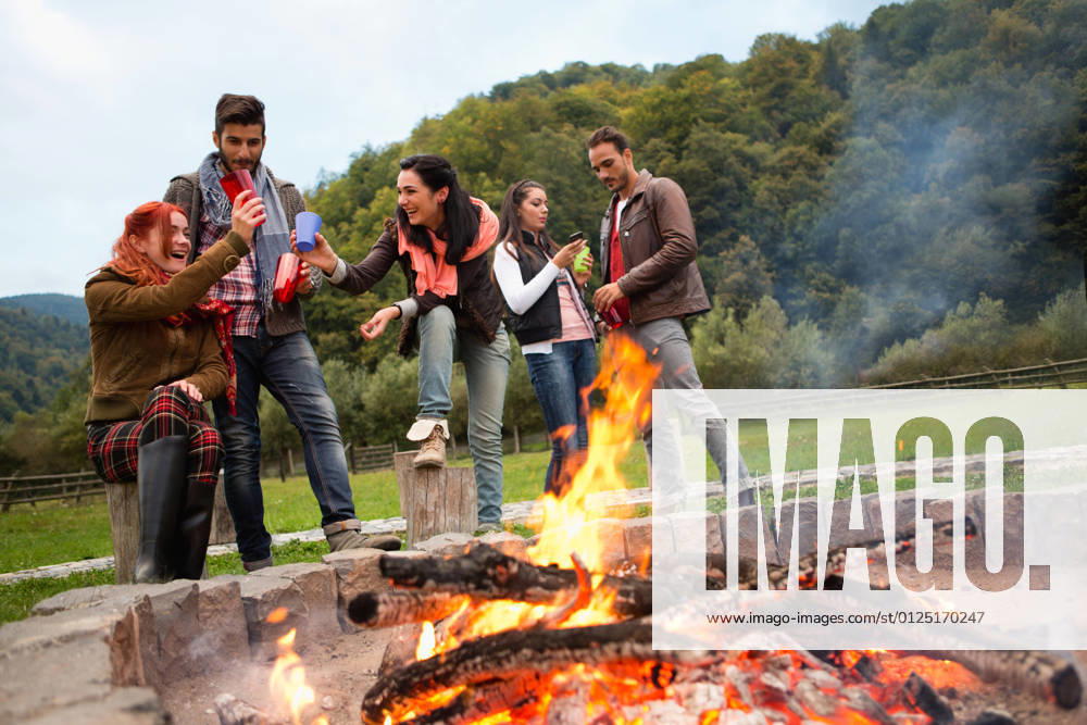 Group of people standing around campfire.