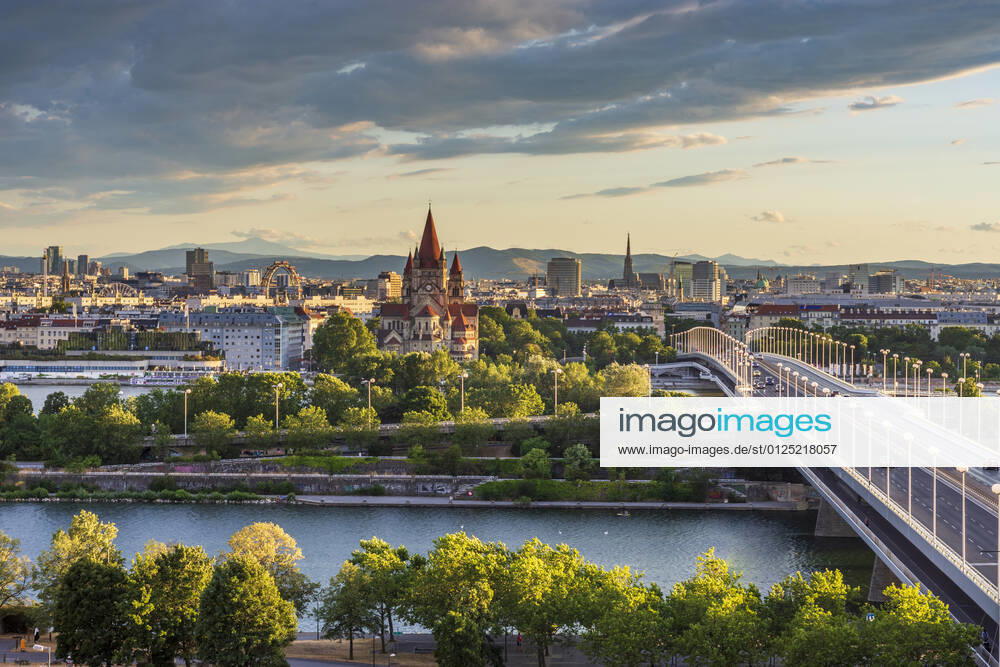 Sunset panorama of Vienna city center from North-East: , river Donau (Danube), island Donauinsel, bridge Reichsbrücke, amusement park Prater, Ferris Wheel, church Franz von Assisi, cathedral Stephansdom (St. Stephen s Cathedral) (from left to right) Wien, Vienna Wien Austria 00. overview