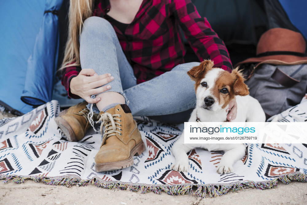 Young woman sitting with dog in tent while camping model released Symbolfoto property released EBBF04217