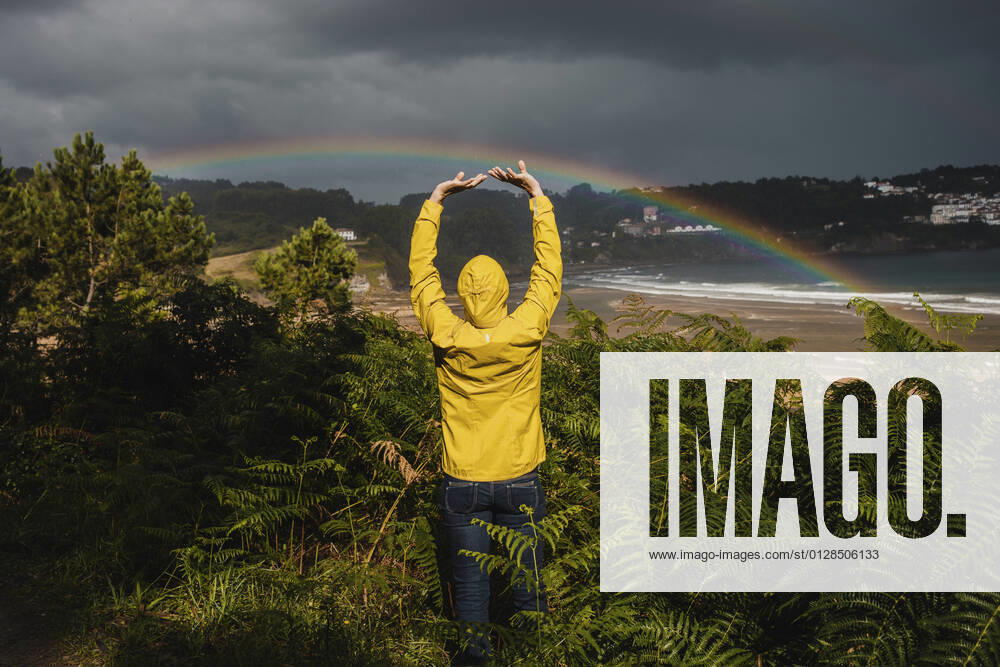 IMAGO Creative: Ende des Sommers Rear view of woman with raised arms by plants during rainy season model released Symbolfoto DMGF00222