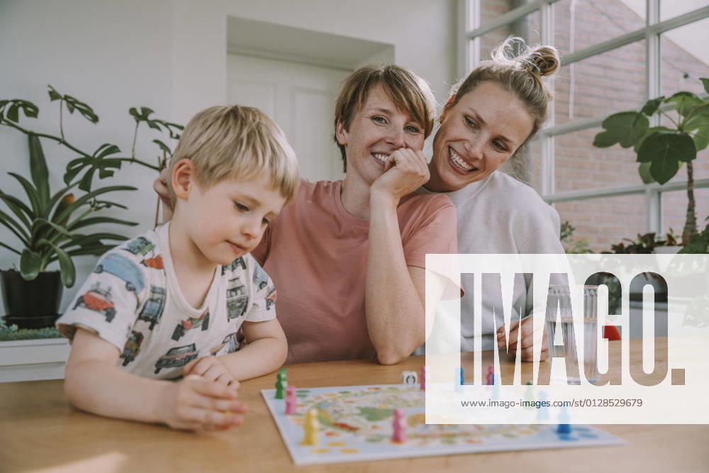 IMAGO Creative: Herbst, in Gesellschaft spielen IMAGO Creative: Pride Month 2022, Engagement der Jugendlichen Mothers watching while son playing board game at home model released Symbolfoto property released MFF06660