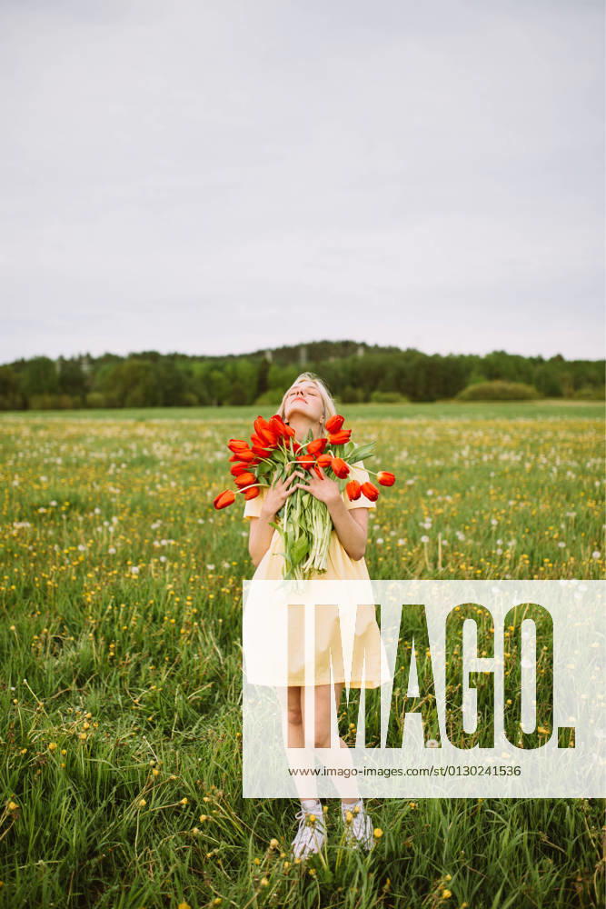 Content female in dress standing with bunch of red tulip flowers in meadow in summer with closed eyes CamilleGirard_GirlWithTulips_20.jpg