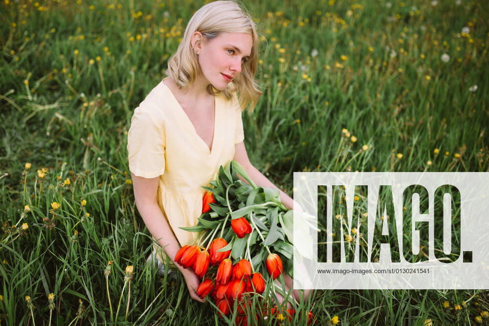 Content female in dress standing with bunch of red tulip flowers in meadow in summer CamilleGirard_GirlWithTulips_24.jpg
