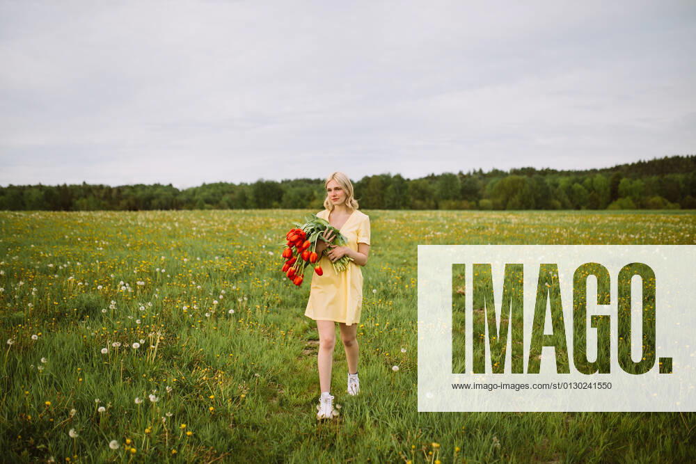 Content female in dress standing with bunch of red tulip flowers in meadow in summer and looking away CamilleGirard_GirlWithTulips_29.jpg