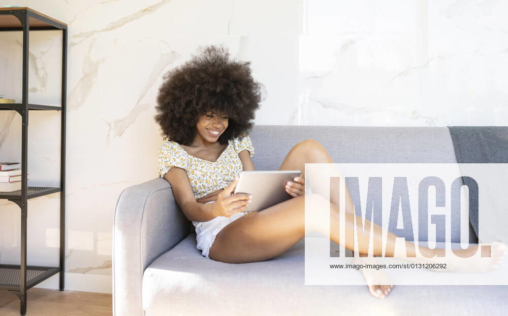 Young woman using digital tablet on sofa at home model released Symbolfoto property released JCCMF03223