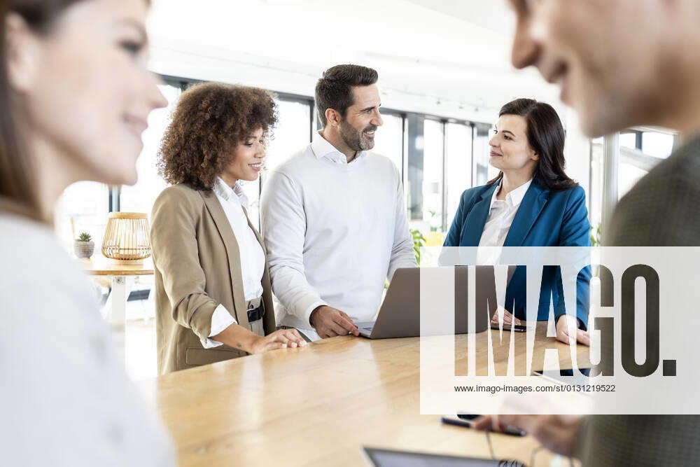 Smiling businessman planning strategy with female colleagues while standing at desk in office model released Symbolfoto property released PESF03047
