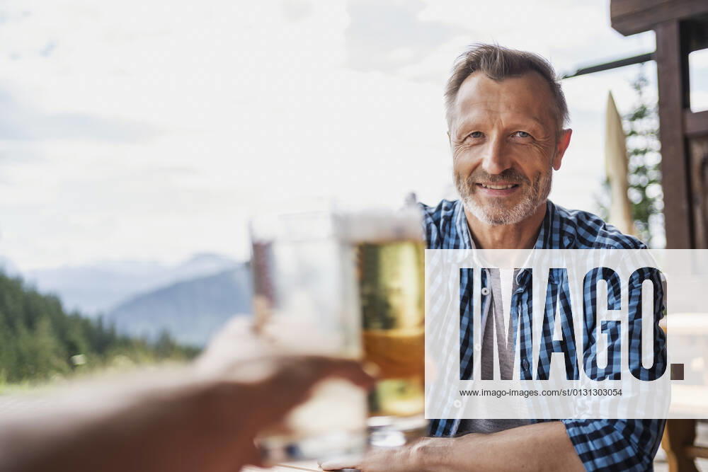Smiling man toasting beer glass with friend at bar model released Symbolfoto DIGF16313