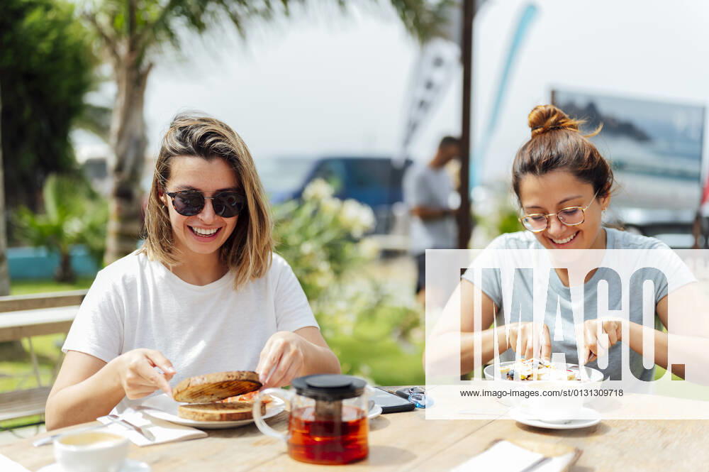 Young female friends having breakfast at table during vacation model released Symbolfoto PGF00740