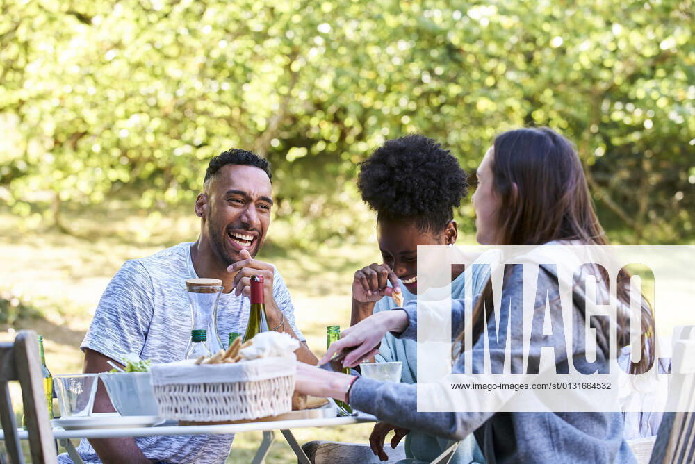 Smiling young friends having food in park