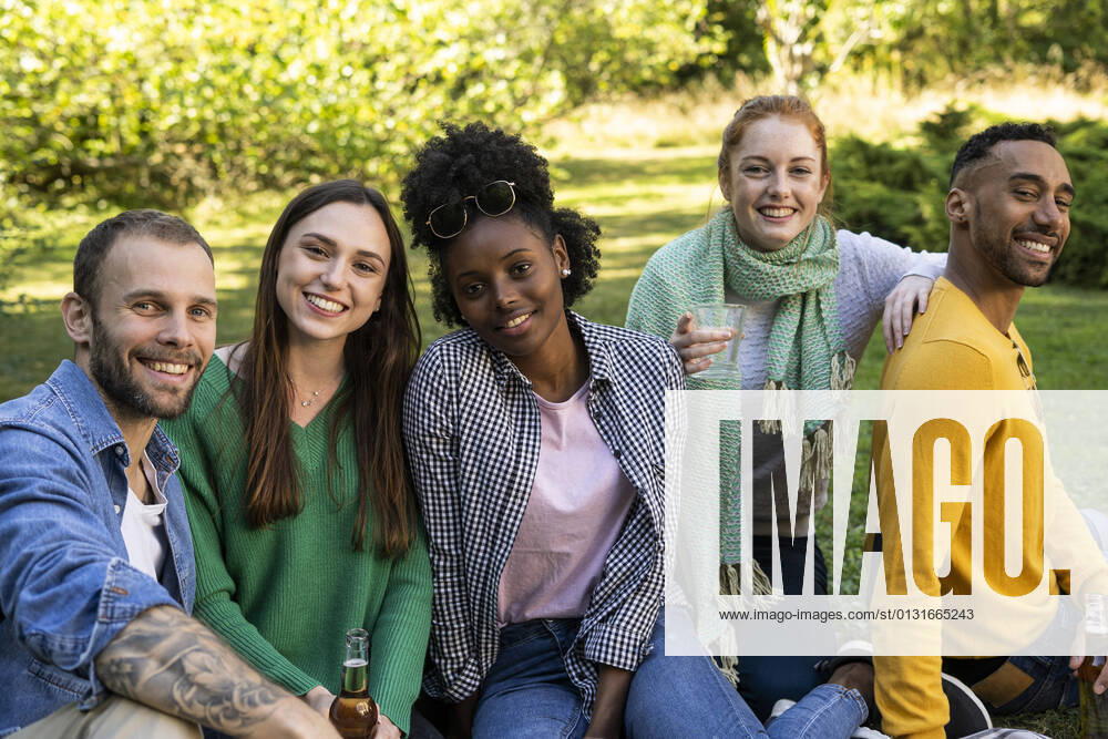 IMAGO Creative: Jahreszeit Frühling, Picknick Smiling young friends sitting together in public park