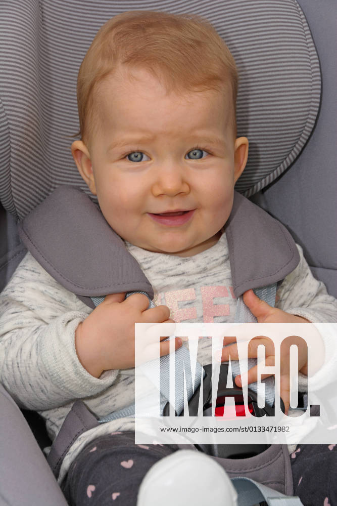 Kleinkind sitzt angeschnallt im Autositz Baby sitzt ordnungsgemäß angeschnallt im Autokindersitz, Hochformat.