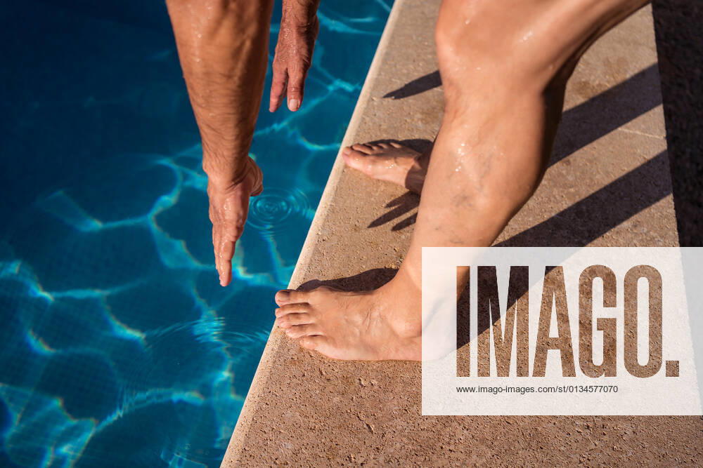 High angle of crop anonymous barefoot person stretching forward while standing on poolside edge near clean water, Model released JuanAlbertoRuiz_FamilyAtPool_149.jpg