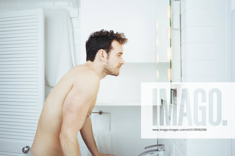 Young man looking in bathroom mirror, 06.01.2015,