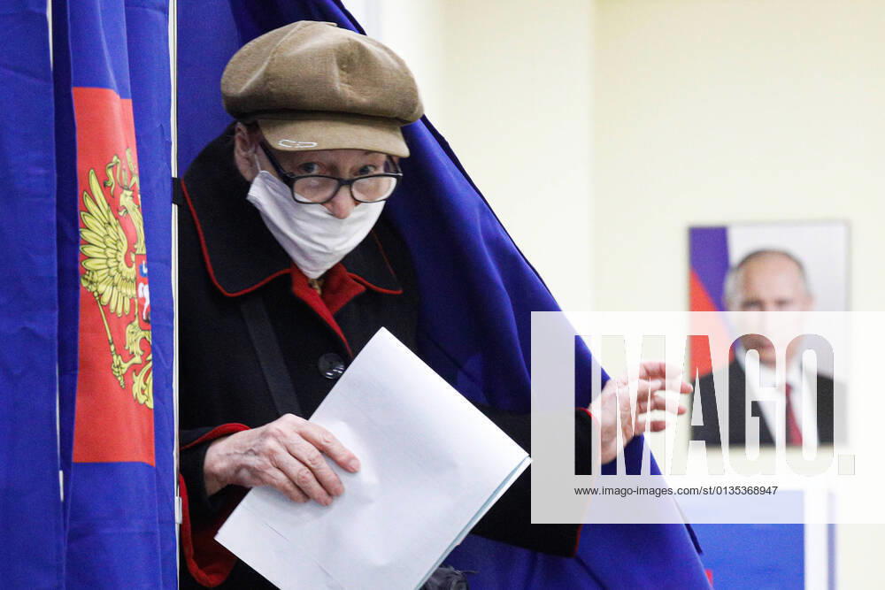 KW37 Russian Parliamentary Election In Moscow A woman at a polling station walks past a portrait of Russian President Vladimir Putin during a vote in the State Duma of the Russian Federation in St. Petersburg. Saint Petersburg, Russia, September 19, 2021 Moscow Russia egorshin-notitle210917_npemM