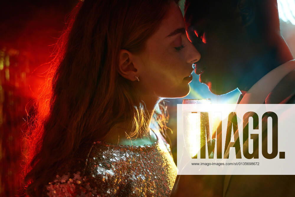 Side view of crop couple with glass on champagne in moment of kiss against shiny light ray looking at each other during party ManuelRuiz_NewYearsEvePartyCouple_33.jpg