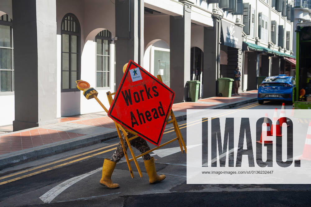 Singapur, Republik Singapur, Asien - Ein Arbeiter im Stadtzentrum traegt eine Vorrichtung mit Strassenschild und Warnlicht waehrend der andauernden Corona-Krise.