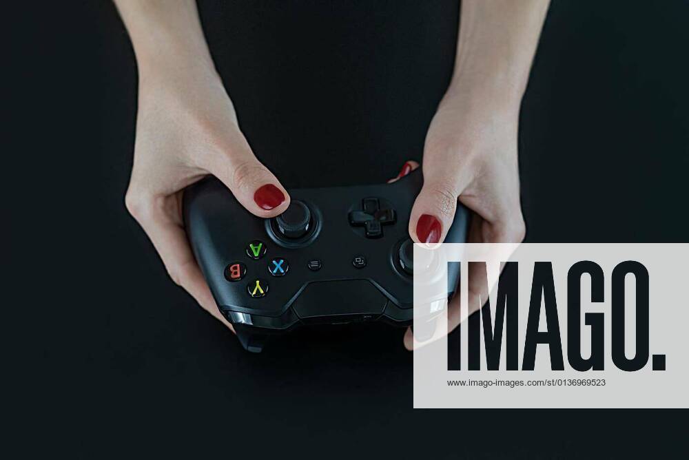 IMAGO Creative, Lifestyle, Gaming Top view of woman hands with red nail polish on fingers holding a logo free modern gaming controller for playing digital video games isolated on black for fun leisure entertainment, 13.10.2020,