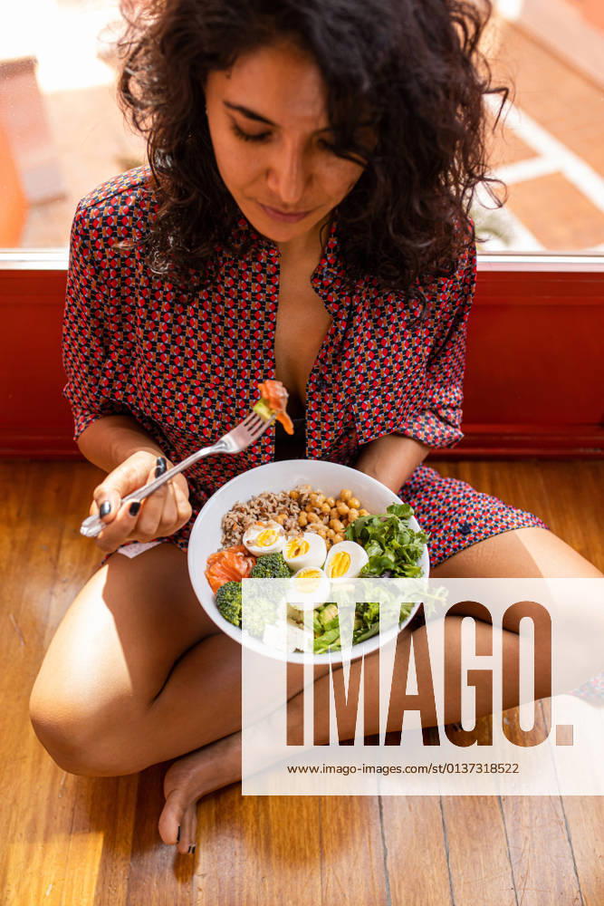High angle of young female with curly hair sitting with crossed legs and eating super food bowl with chickpea chopped eggs broccoli DavidFuentes_HealthyFood_21.jpg