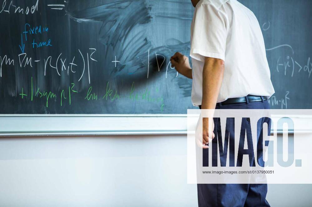 Teacher teaching mathematics while pointing at blackboard in classroom model released, Symbolfoto, 13.10.2020,