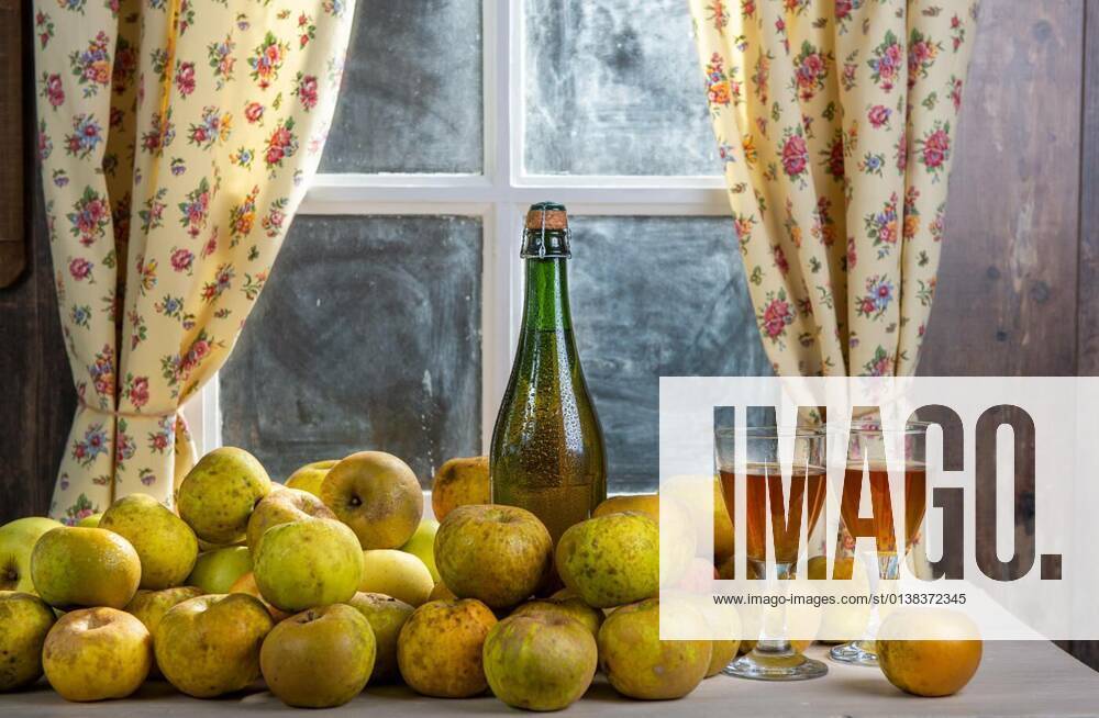 Bottle and glasses of cider with apples, near the window, in rustic house, 13.10.2020,