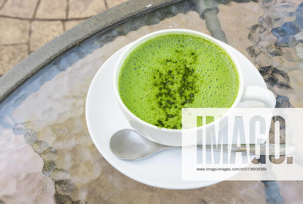 Closeup a cup of matcha latte or green tea on glass table background