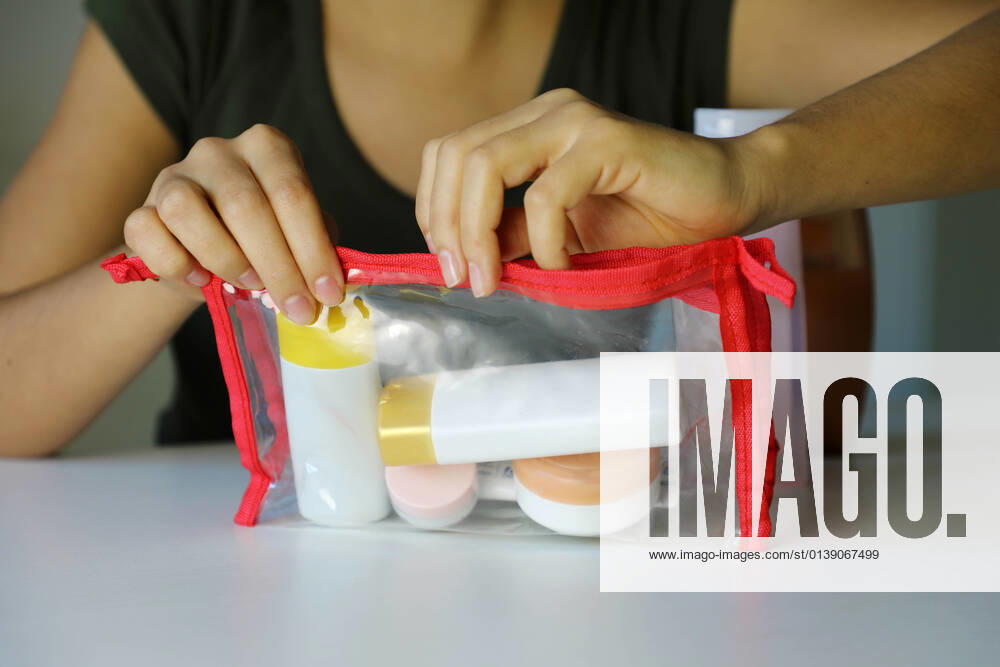 Woman closing trasparent bag with travel kit for transporting cosmetics on airplane