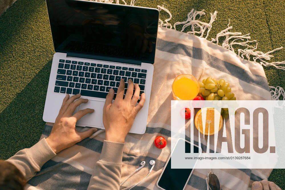 IMAGO Creative: Jahreszeit Frühling, Picknick Hands using laptop and typing in summer grass Hands using laptop and typing in summer grass Vietnam Vietnam