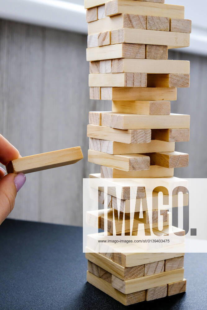 IMAGO Creative: Jahreszeit Winter, Fantasievoll drinnen spielen Building from wooden blocks. Game for family of wooden bars. Wood blocks stack game with Hand on background. Block tower with architecture model. Building from wooden blocks. Wood blocks stack game with Hand on background. Conceptual of Teamwork. Block tower with architecture model, Risk of management and strategy plan, growth business success process