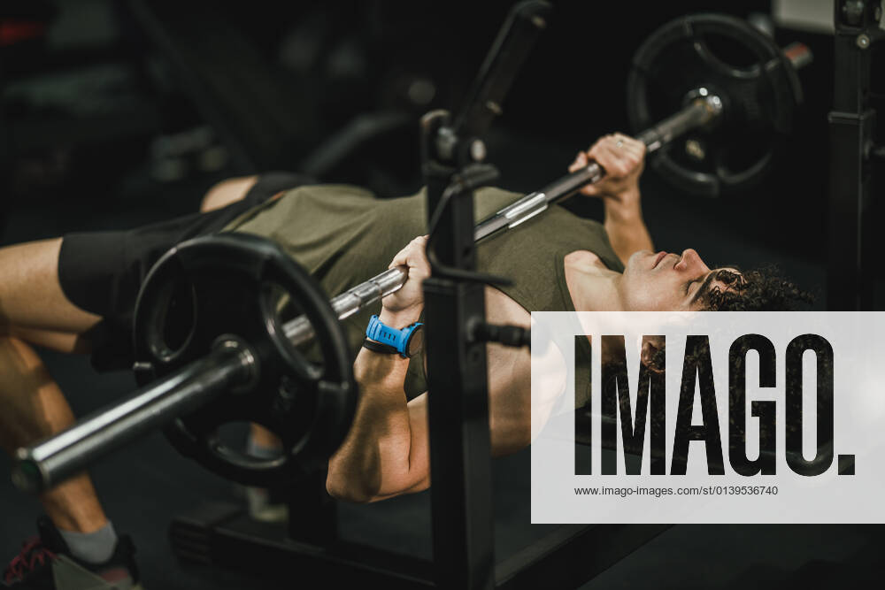 Stay Consistent, Stay Fit Shot of a muscular guy working out at the hard training in the gym. He is pumping up chest muscle with heavy weight.