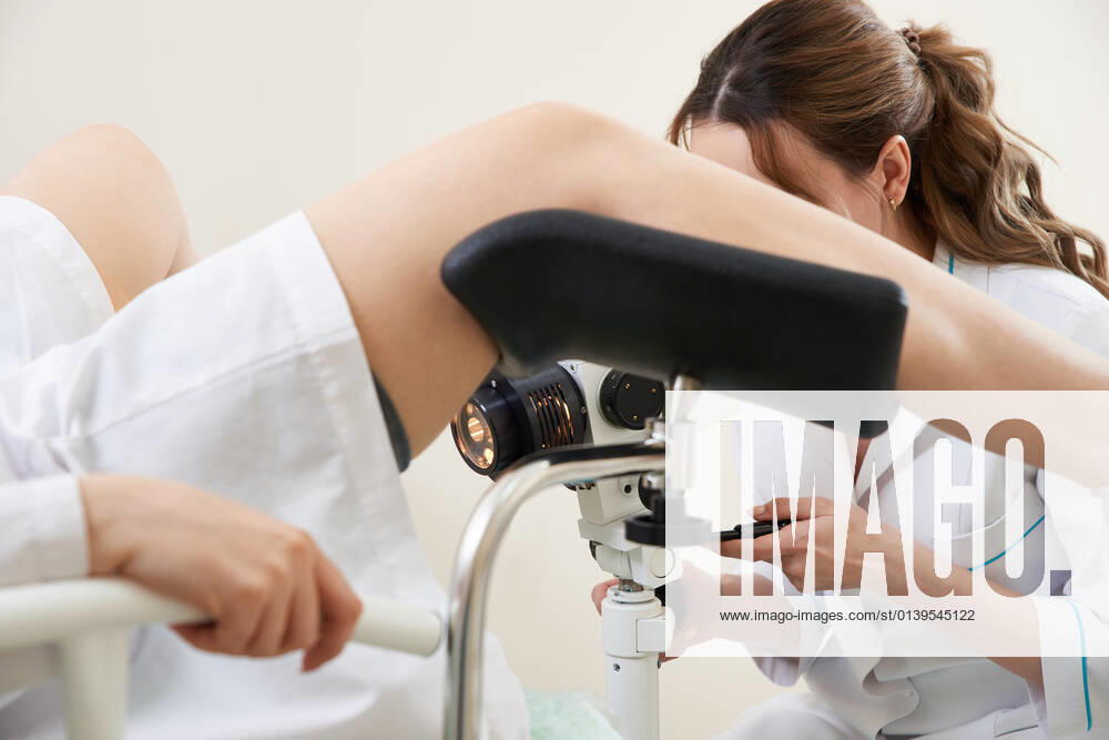 Gynecologist examining a patient with a microscope in modern medical clinic woman gynecologist working with colposcope and makes microscopic investigation in clinic
