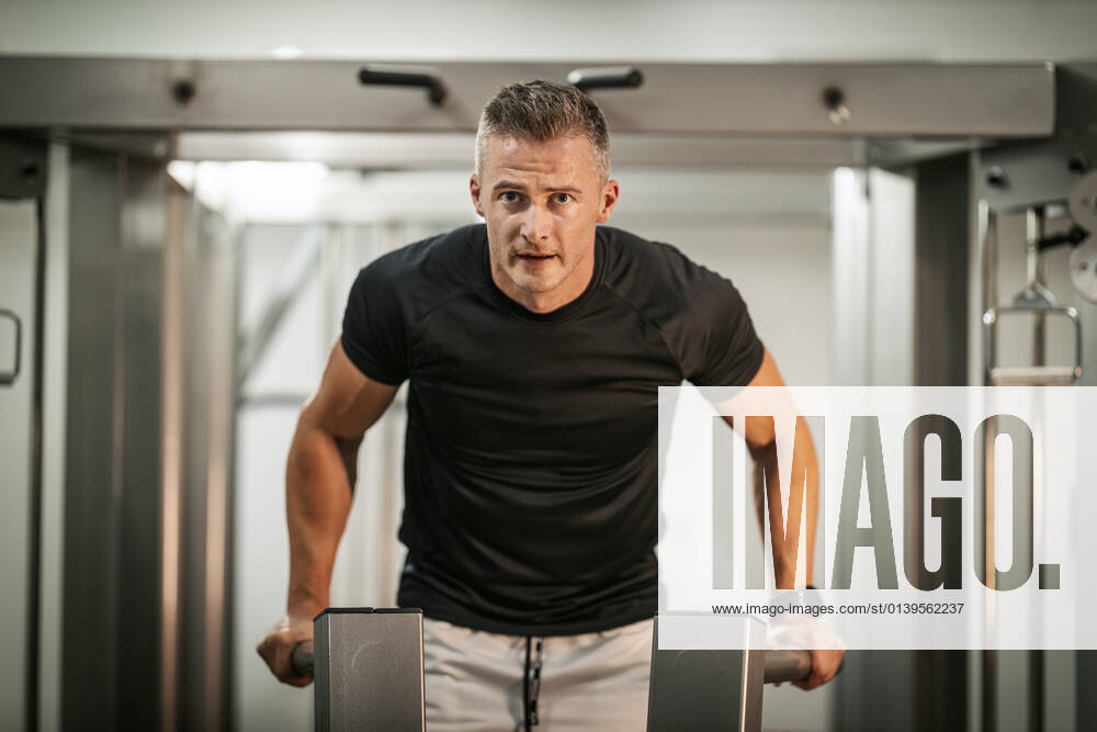 Fitness For Healthy Lifestyle Muscular young man doing hard exercises on machine during a strength training workout at the gym.