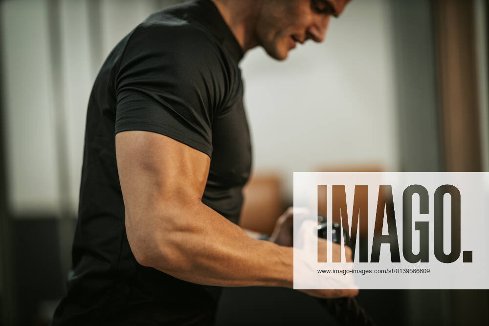 Fitness For Healthy Lifestyle Muscular young man in sportswear focused on doing cable triceps pulldowns during a strength training workout at the gym.