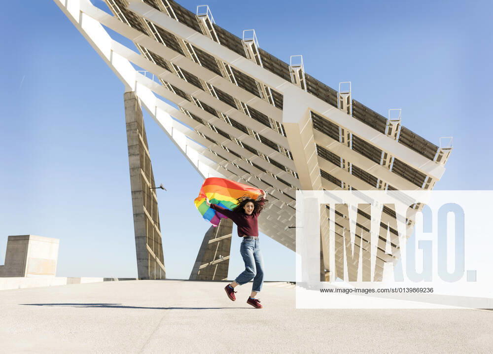 Woman holding rainbow flag near solar energy panel model released Symbolfoto VABF04360