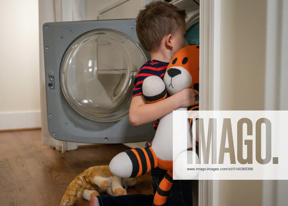 IMAGO Creative: Jahreszeit Winter, Fantasievoll drinnen spielen Young boy putting stuffed tiger into the washing machine Arlington, Virginia, United States CR_SUSU21091477-829305-01 ,model released, Symbolfoto
